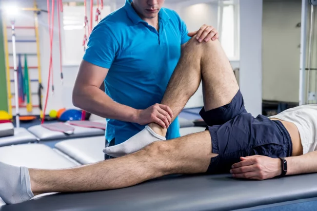 ผู้เชี่ยวชาญด้านวิทยาศาสตร์การกีฬากำลังทำ Sport Massage และฟื้นฟูกล้ามเนื้อขา