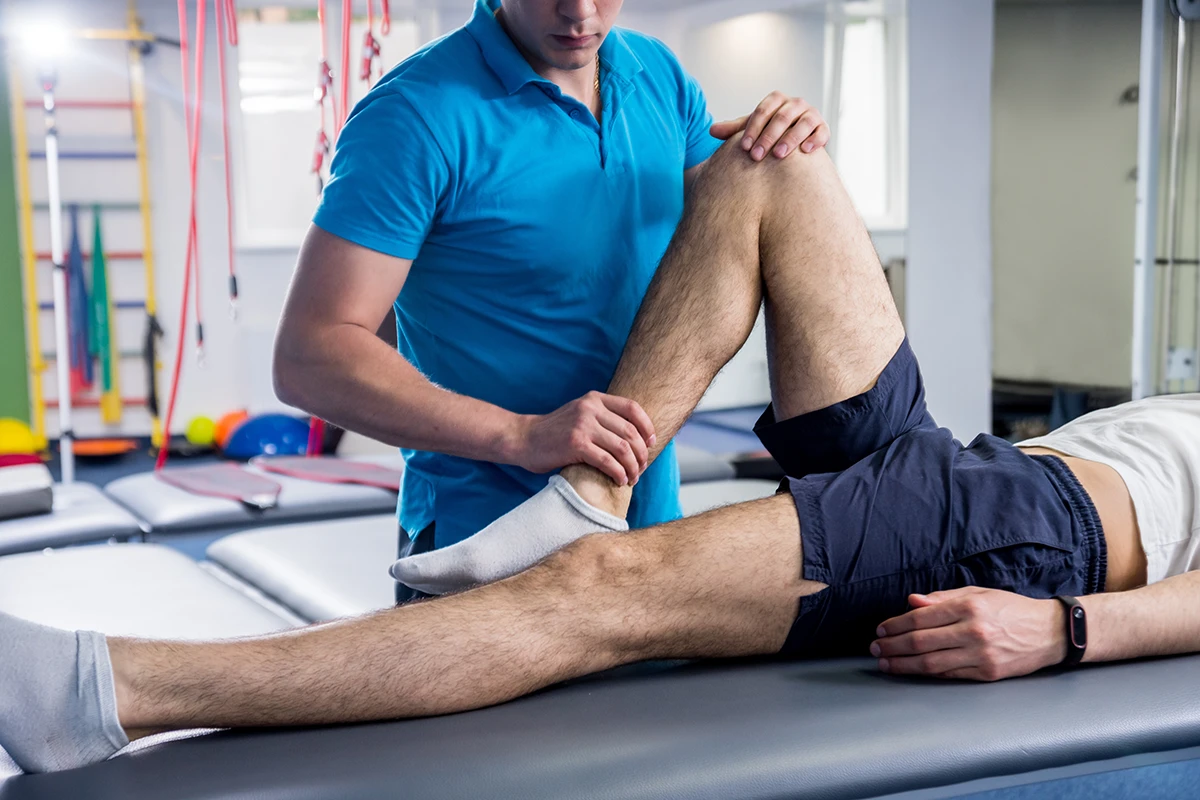 ผู้เชี่ยวชาญด้านวิทยาศาสตร์การกีฬากำลังทำ Sport Massage และฟื้นฟูกล้ามเนื้อขา